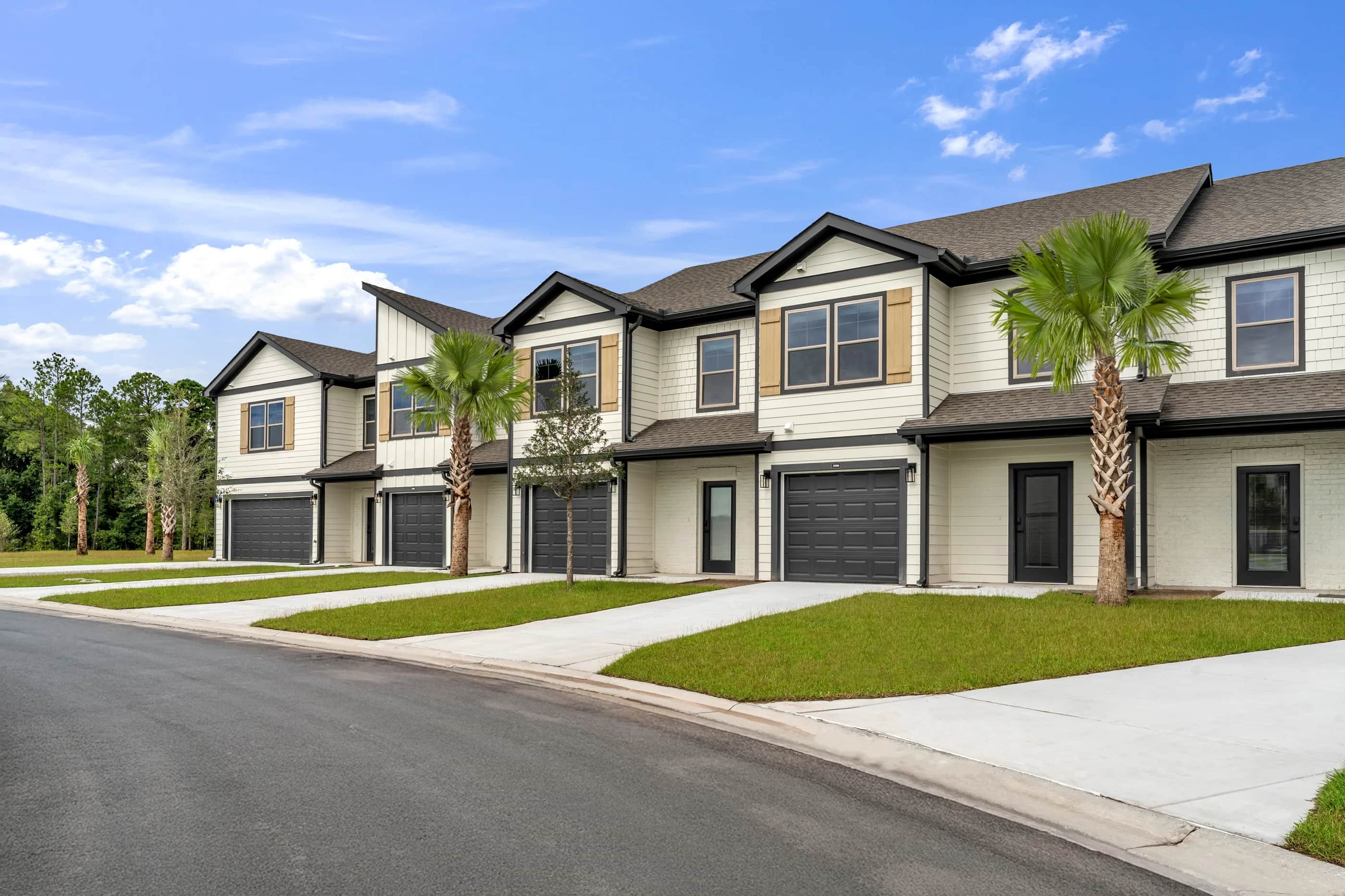 A street of brand-new Pointe Villas townhomes with palms and private garages